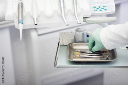 Close up of a dentist hand choosing an instrument from dental tools photo