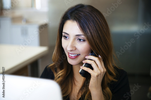 Happy female receptionist using cordless phone in dentist's office photo