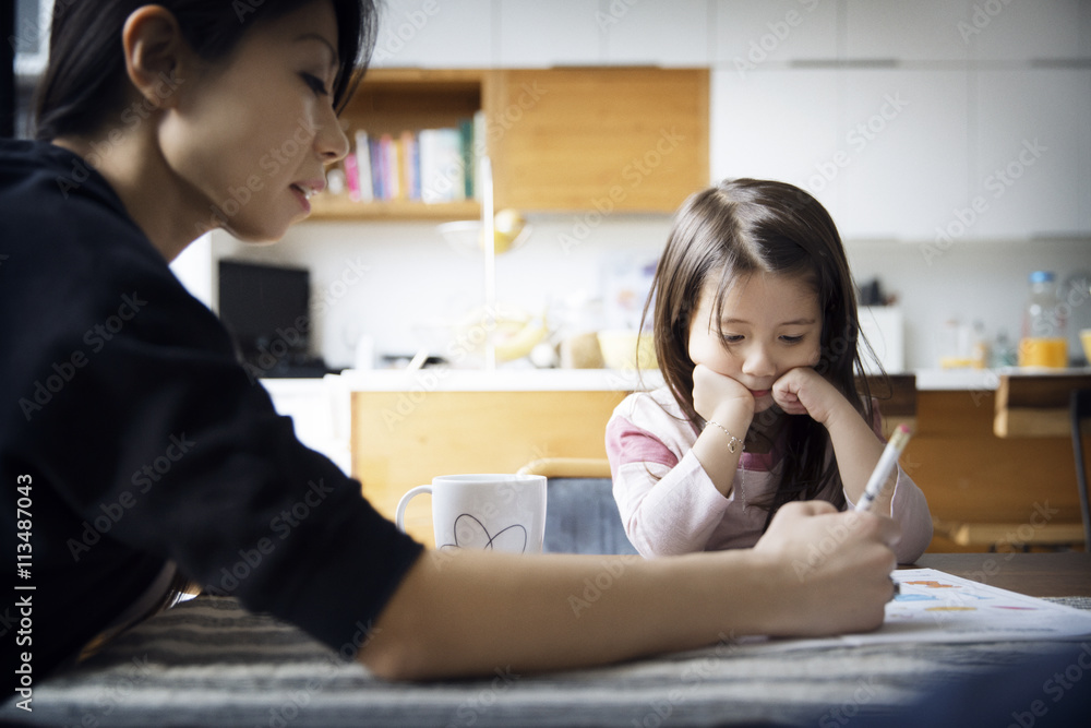 Mother teaching daughter on table at home Mother teaching daughter on table at home