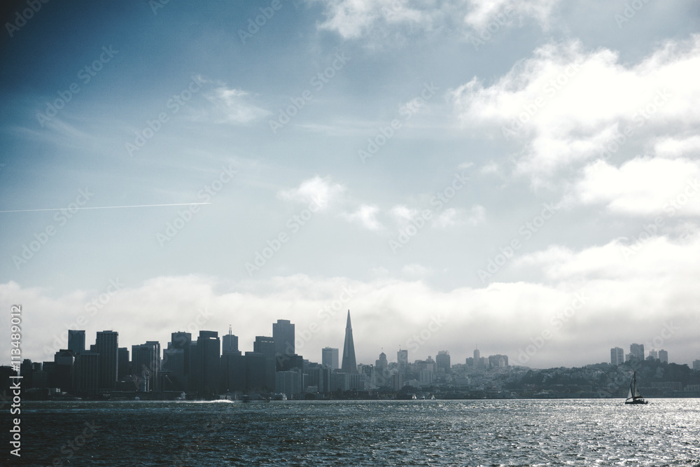 View of city skyline by sea against cloudy sky View of city skyline by sea against cloudy sky