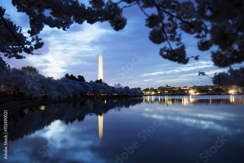Washington Monument by lake against cloudy sky at dusk