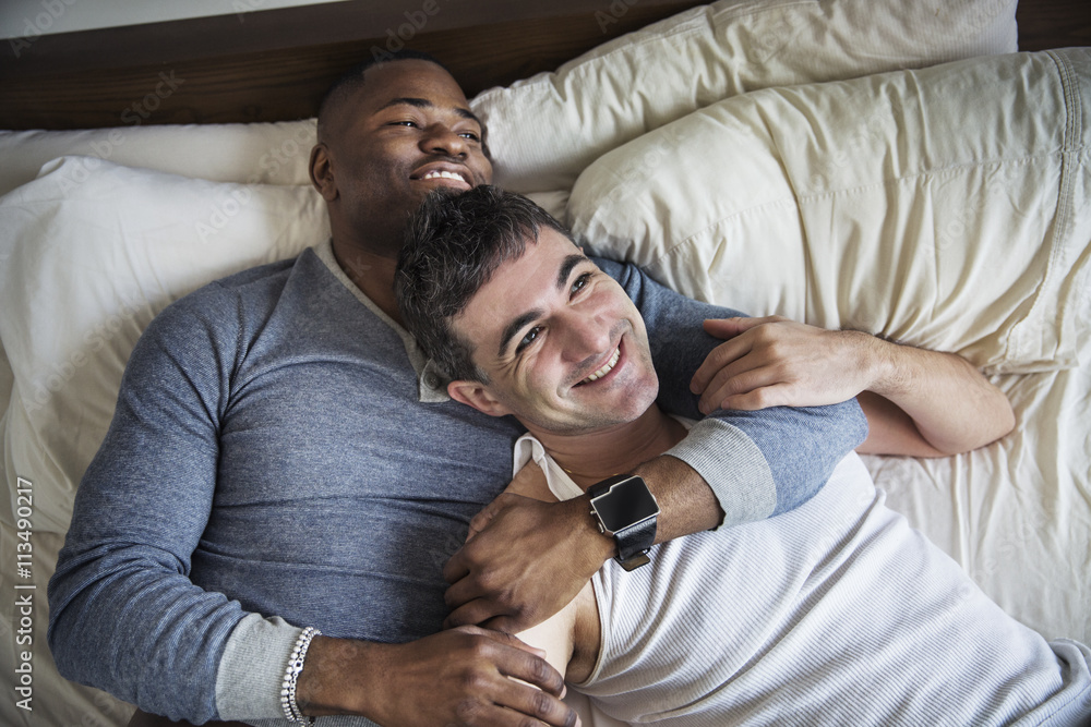 high angle view of gay couple lying on bed high angle view of gay couple lying on bed