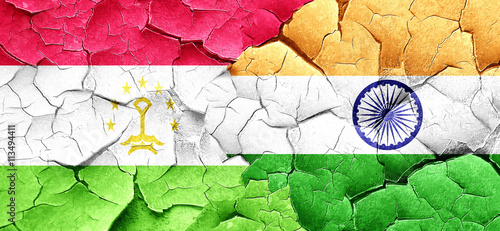 Tajikistan flag with India flag on a grunge cracked wall