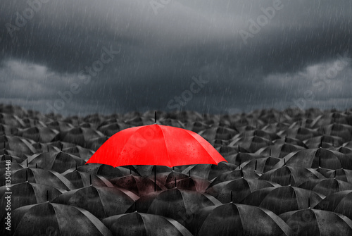 red umbrella in mass of black umbrellas