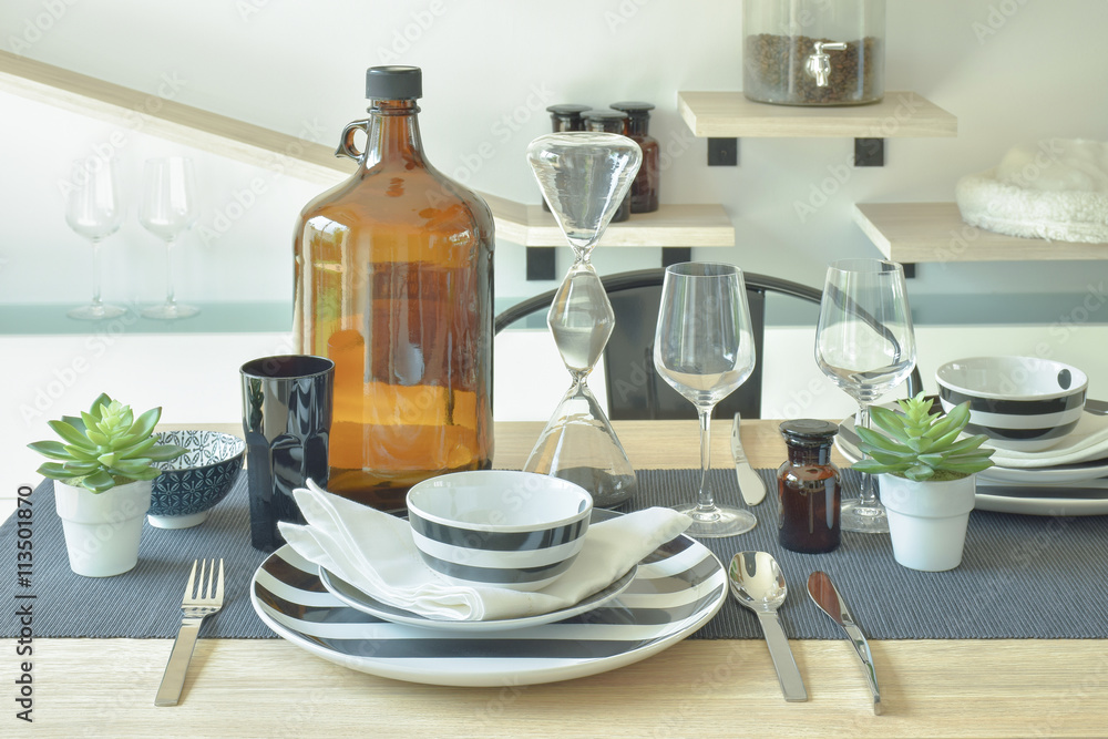 Fototapeta premium Striped chinaware, wine glass and bottle setting on wooden dining table