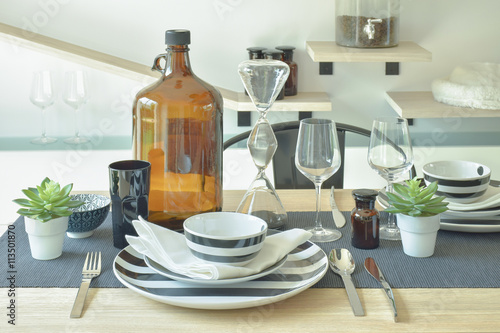 Striped chinaware, wine glass and bottle setting on wooden dining table