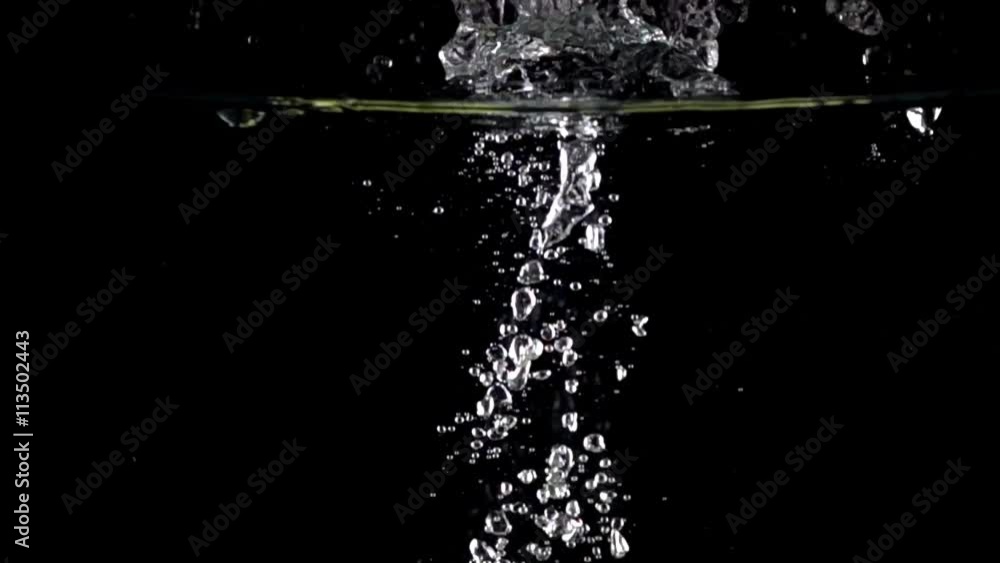 Two green apples fall down in water against black background, super slow motion Two green apples fall down in water against black background, super slow motion