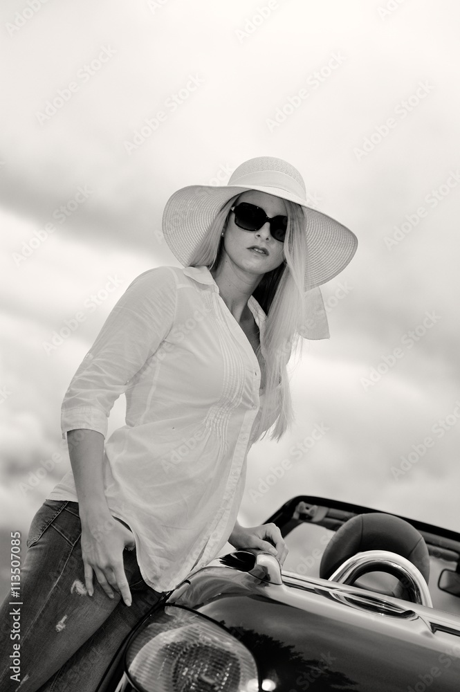 Junge blonde Frau mit Sonnenbrille, Hut und Cabrio Stock-Foto | Adobe Stock
