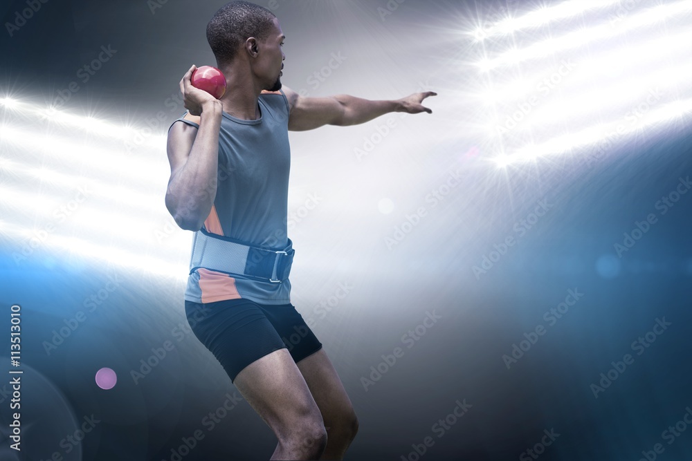 Rear view of sportsman practising shot put against spotlights Rear view of sportsman practising shot put against spotlights
