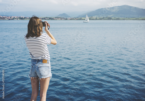 Hipster photograph on vintage camera or technology, mock up. Girl using vintage camerae on blue sea and yacht background close. Blurred backdrop. Mockup front view. Copy space for text photo