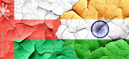 Oman flag with India flag on a grunge cracked wall