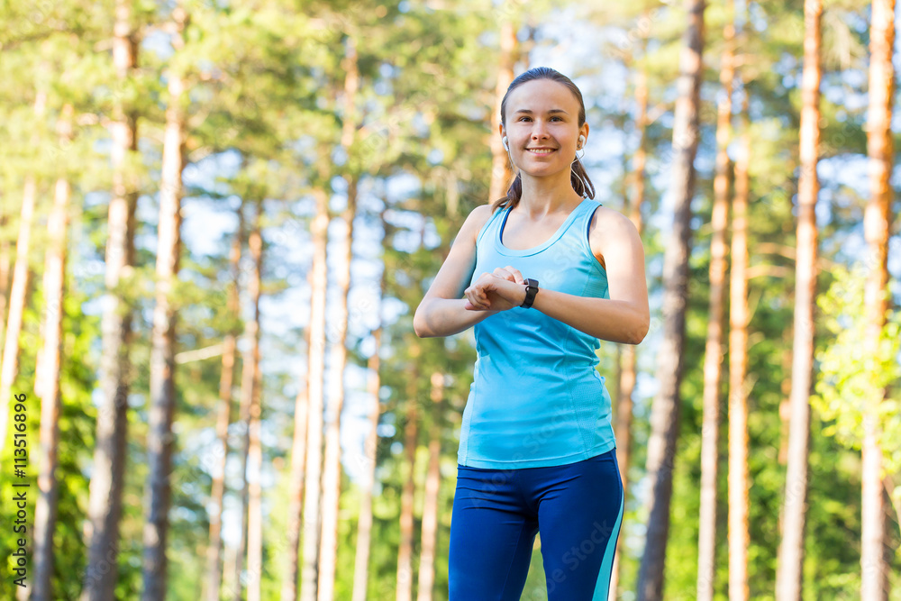 Runner woman with heart rate monitor for running in forest. Runner woman with heart rate monitor for running in forest.