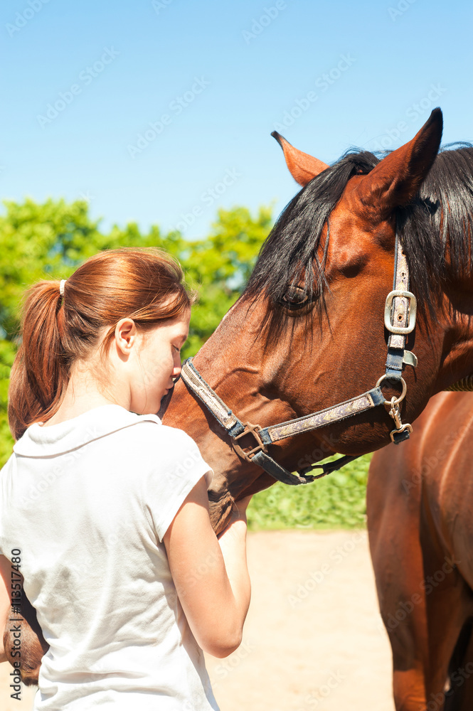 Obraz premium Young redhead teenage girl kissing her favorite chestnut horse.