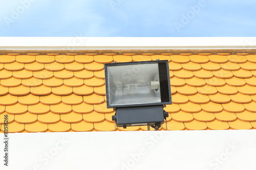 Halogen, Metal halide floodlight lamp installed on roof top with yellow scale background