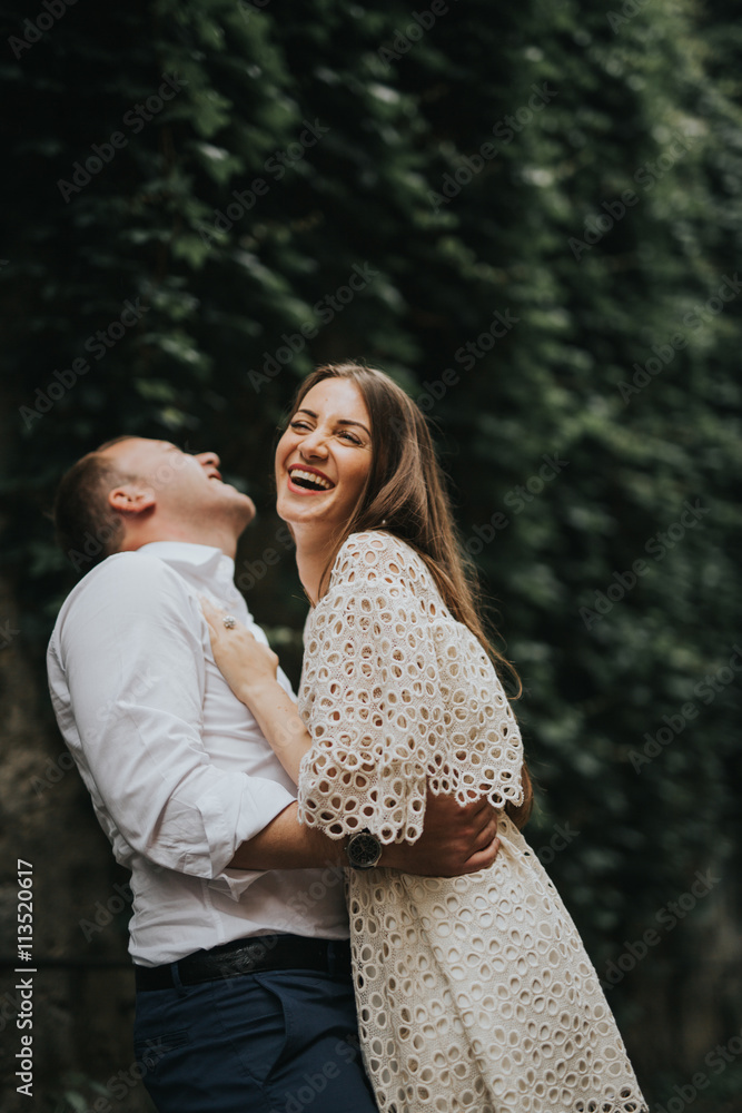 Naklejka premium Young cute couple honeymoon posing in the street holding their hands on dating in a beautiful place italy near ocean and mountains, hug, smile and talk to each other 