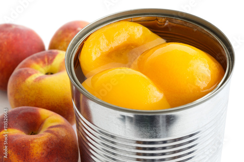 Detail of open can of peach halves in syrup on white background
