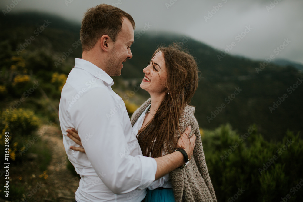 Fototapeta premium Young cute couple honeymoon walks holding their hands on dating in a beautiful place italy near ocean and mountains, hug, smile and talk to each other 