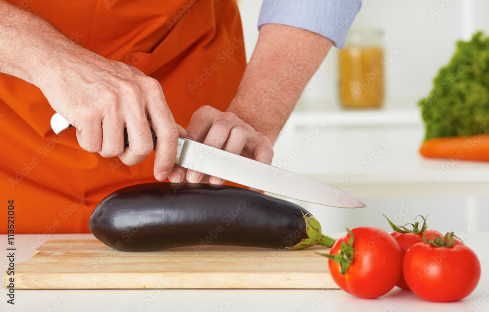 Closeup man's hands cutting vegetables on a work surface in a kitchen. Closeup man's hands cutting vegetables on a work surface in a kitchen.