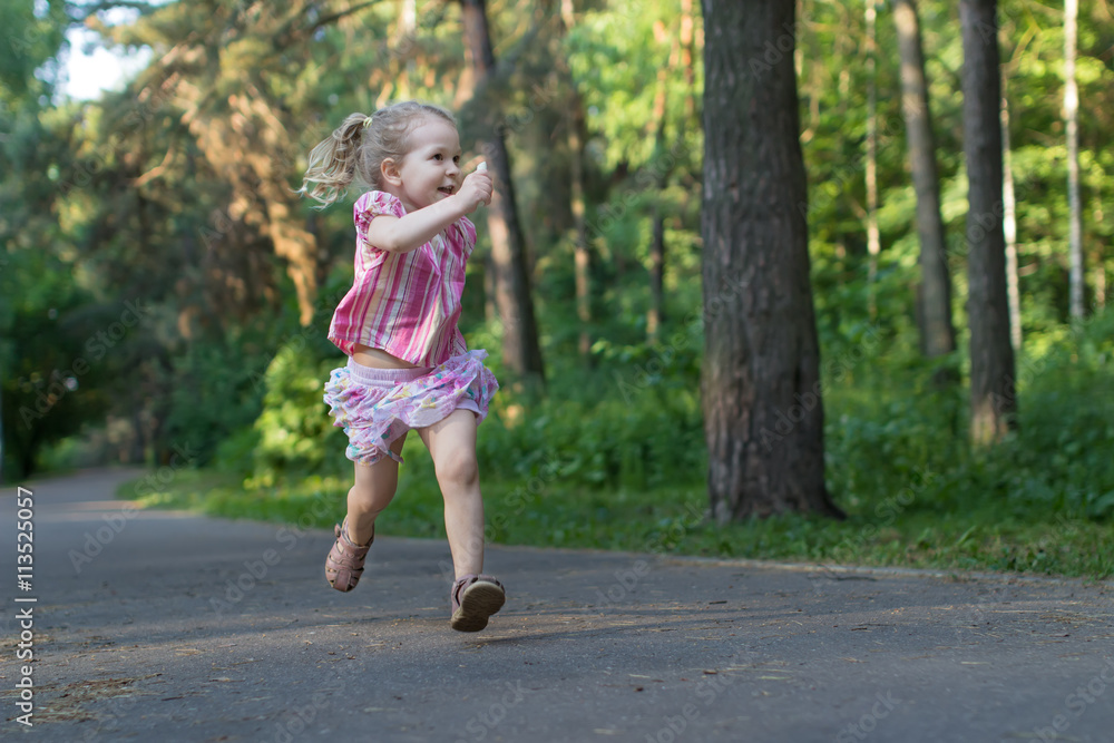 Exited three years old runner girl on asphalt park footpath holding piece of sidewalk chalk Exited three years old runner girl on asphalt park footpath holding piece of sidewalk chalk