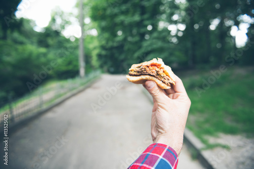 Man is eating in the park and enjoying delicious food