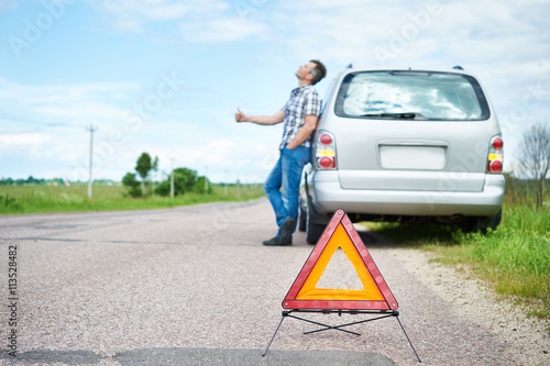 Man standing on road near car and waiting help