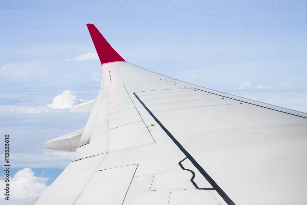 Plane wing on cloudy blue sky background