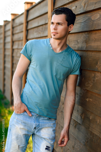 Portrait of macho young handsome guy in blue shirt outdoor at sunset