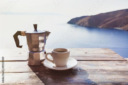 Fototapeta Naklejka Na Ścianę i Meble -  Cup of coffee on a table with beautiful sea view at the background
