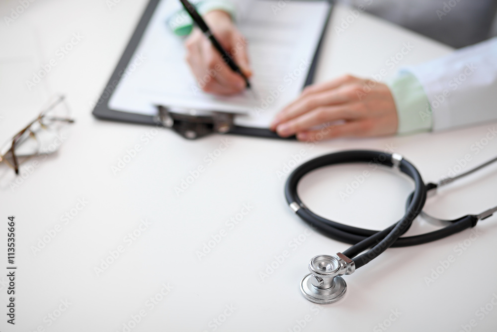 Close up of unknown female doctor sitting at the table near the window in hospital and typing at laptop computer Close up of unknown female doctor sitting at the table near the window in hospital and typing at laptop computer