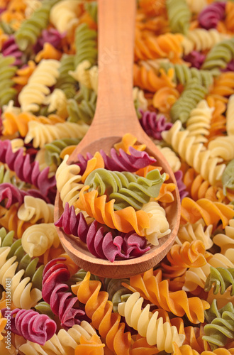 Colored uncooked italian pasta fusilli in a spoon