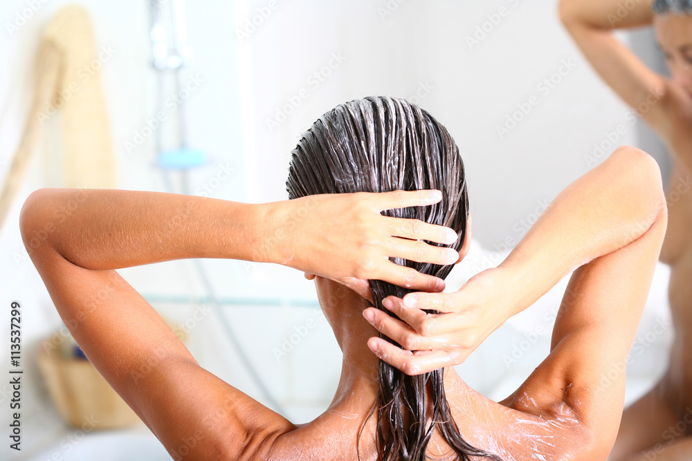 femme dans sa salle de bain soignant ses cheveux - obrazy, fototapety, plakaty 