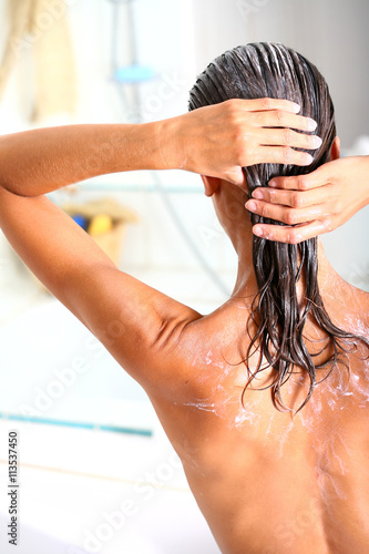 femme dans sa salle de bain soignant ses cheveux