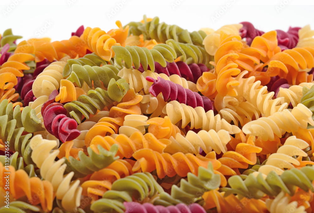 Heap of colored uncooked italian pasta fusilli on a white Heap of colored uncooked italian pasta fusilli on a white