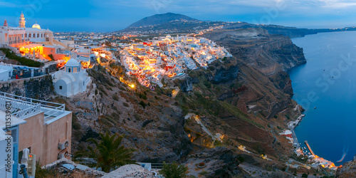 Fira, main town of the island Santorini, sea, white houses and church during twilight blue hour, Greece