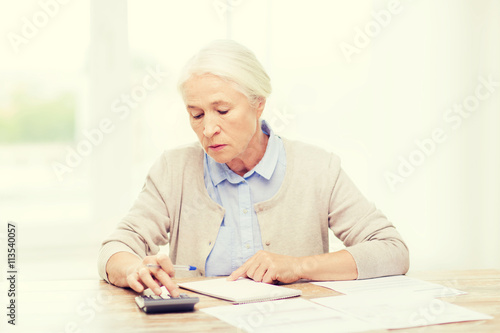 senior woman with papers and calculator at home
