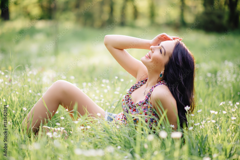 sunny summer day, a beautiful young woman lying on the grass
