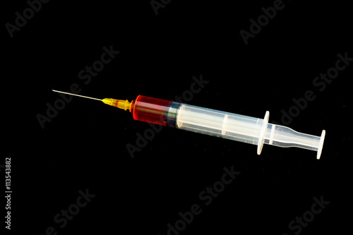 Syringe with blood on a black background