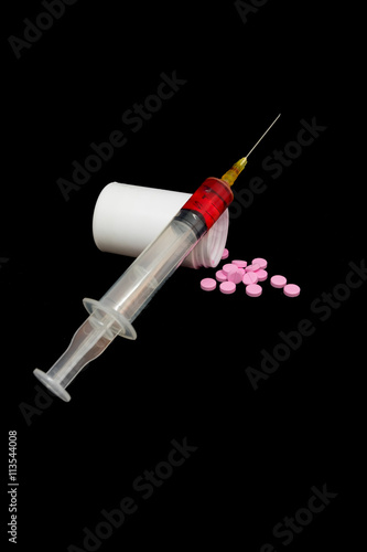 syringe with blood and medicien pill isolated on black backgroun photo