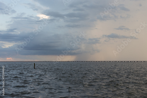 Stormy rainclouds over dark water, Lake Pontchartrain bridge early sunset photo