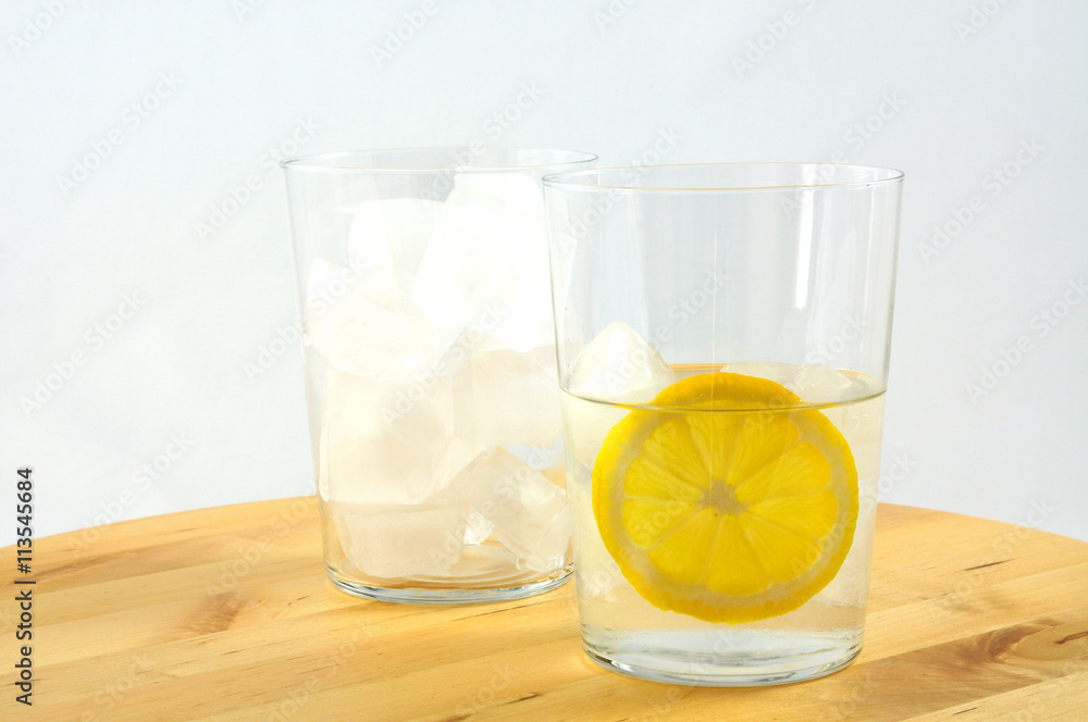bicchieri con acqua, ghiaccio e fetta tonda di limone su un tavolo di legno bicchieri con acqua, ghiaccio e fetta tonda di limone su un tavolo di legno