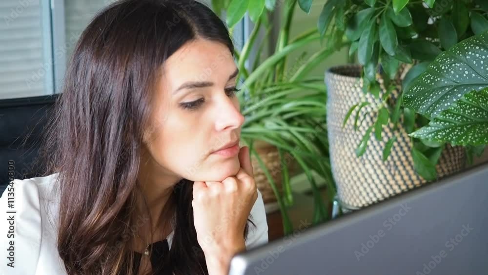 Businesswoman working on computer in the office. She is looking on monitor and starts smiling. Front view. Businesswoman working on computer in the office. She is looking on monitor and starts smiling. Front view.