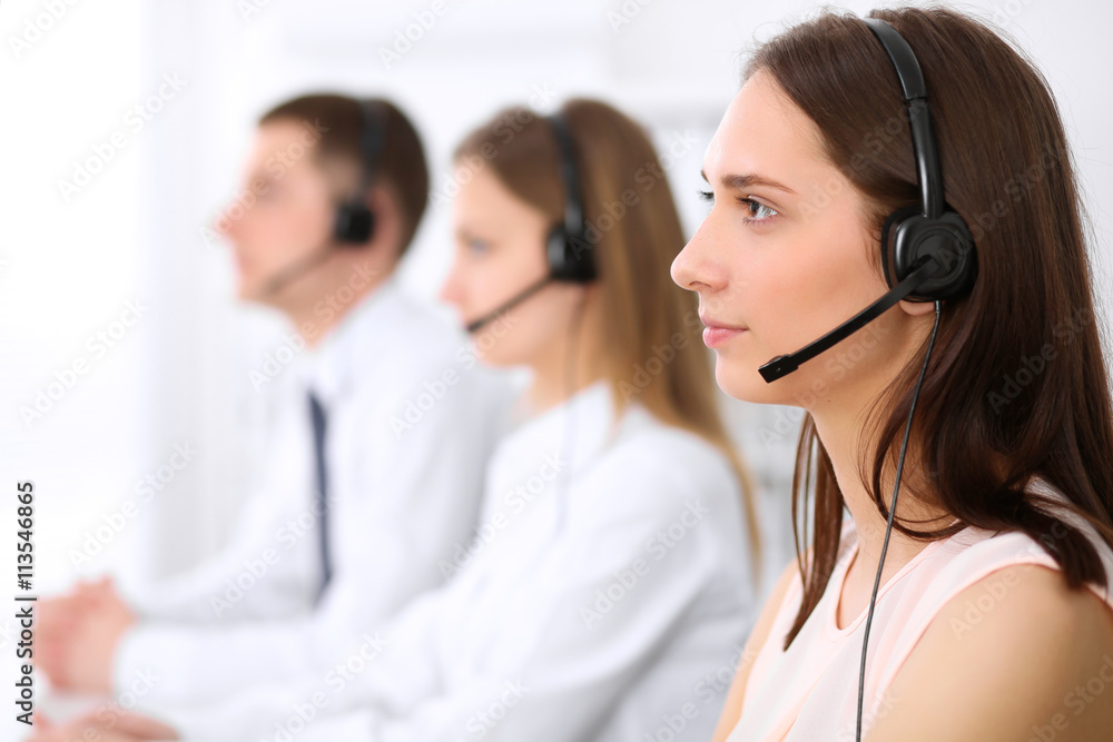 Young beautiful business woman in headset. Call center. Male call operator in headset at the background. Young beautiful business woman in headset. Call center. Male call operator in headset at the background.
