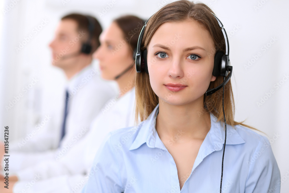 Young beautiful business woman in headset. Call center. Male call operator in headset at the background. Young beautiful business woman in headset. Call center. Male call operator in headset at the background.