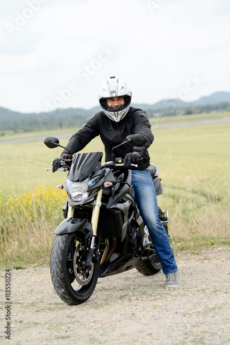 handsome young man biker with white helmet riding black motorcycle