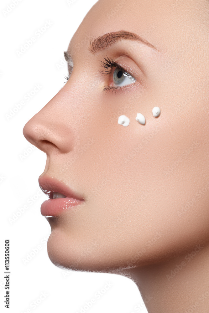 Beautiful face of young woman with cosmetic cream on a cheek. Sk Beautiful face of young woman with cosmetic cream on a cheek. Sk