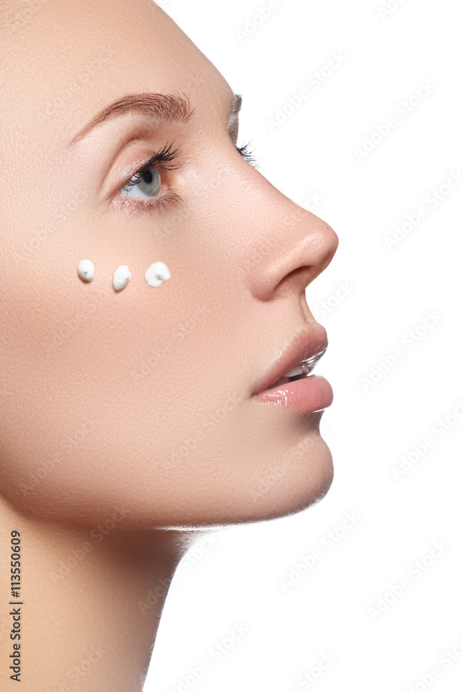 Beautiful face of young woman with cosmetic cream on a cheek. Sk Beautiful face of young woman with cosmetic cream on a cheek. Sk