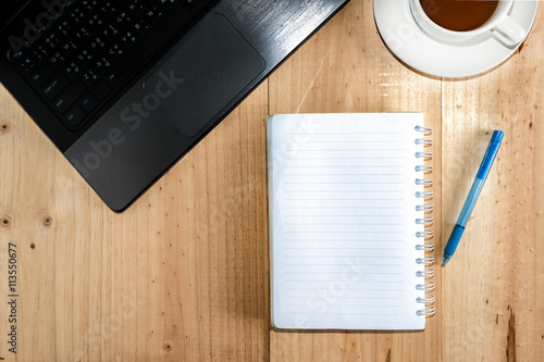 Wood desk with office supplies and white cup of tea  top view