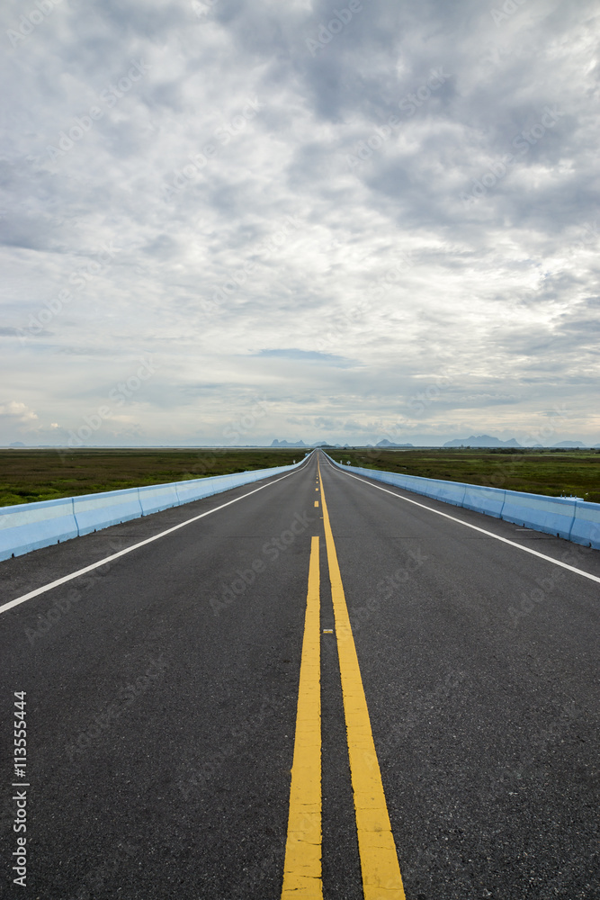 Empty road and the yellow traffic lines with clouds.