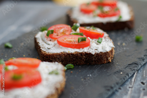 Bruschetta with feta cheese, fresh tomatoes and spices on a black rustic table