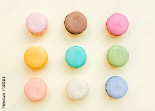 Sweet colorful French macaroon biscuits on pastel yellow background